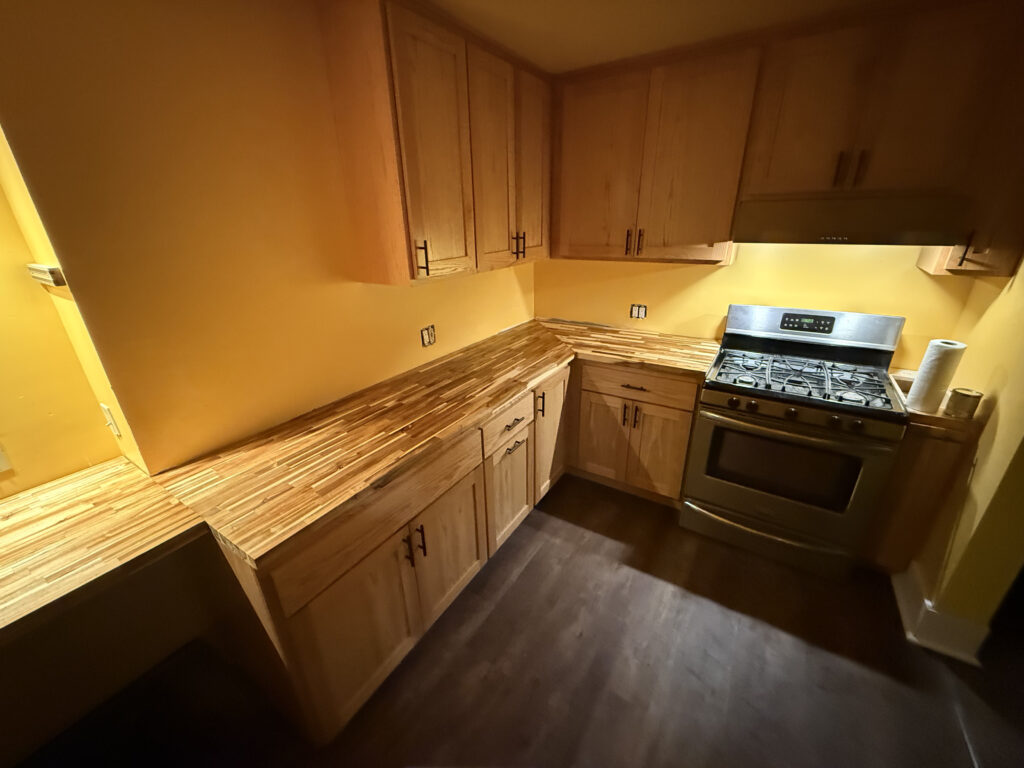 Kitchen cabinet and countertop upgrade in Springfield, Oregon featuring natural wood cabinets, butcher block countertops, stainless steel range, and dark flooring.