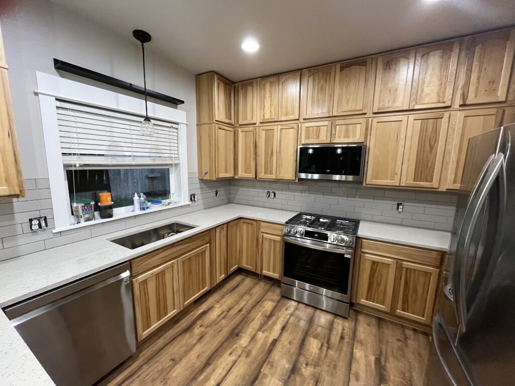 Kitchen remodel in Eugene, Oregon featuring natural wood cabinets, quartz countertops, subway tile backsplash, stainless steel appliances, and wood-look flooring.