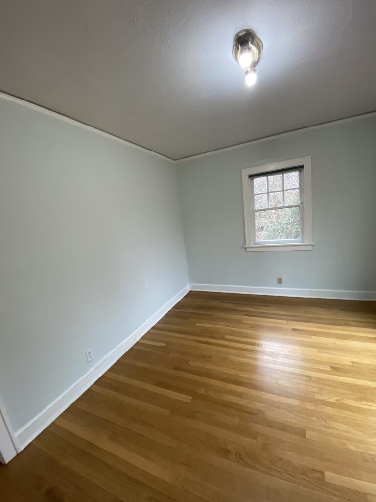 Interior painting in Creswell, Oregon with light blue walls, white trim, hardwood floors, and a finished bedroom.