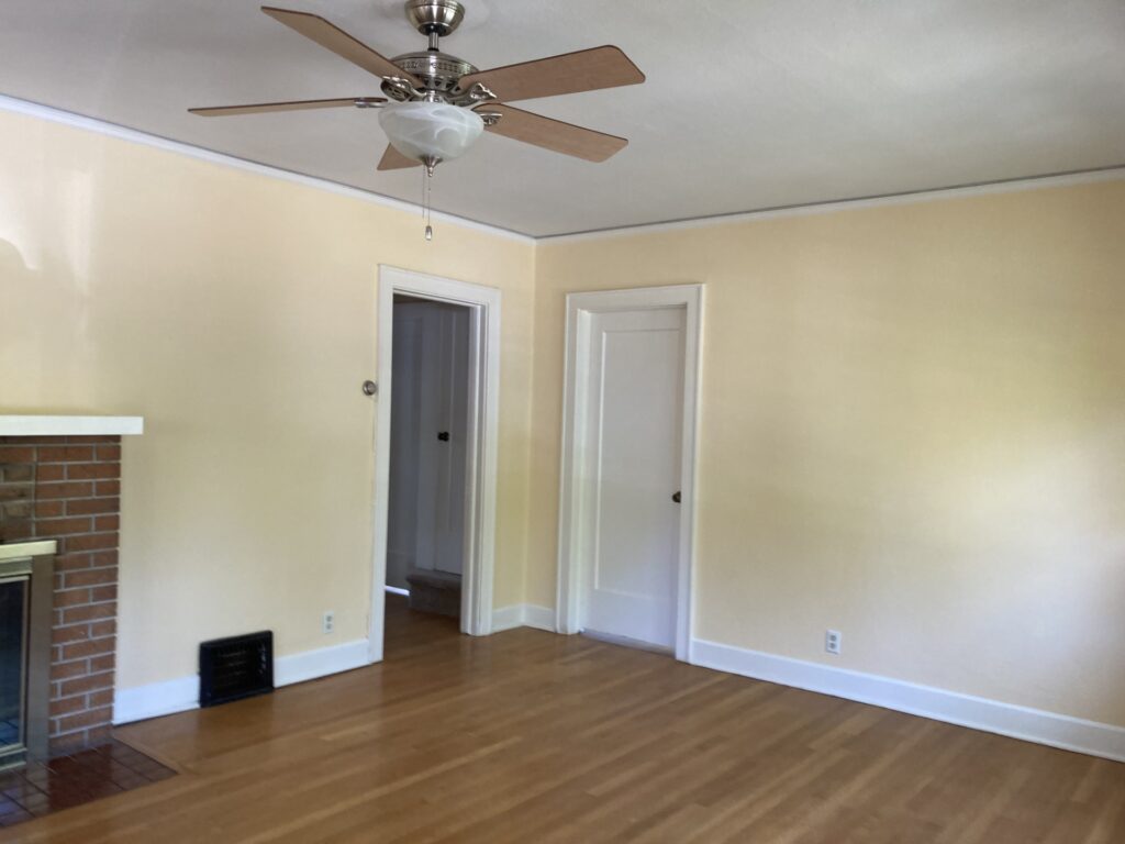 Interior painting in Pleasant Hill, Oregon featuring warm yellow walls, white trim, hardwood floors, and a living room fireplace.
