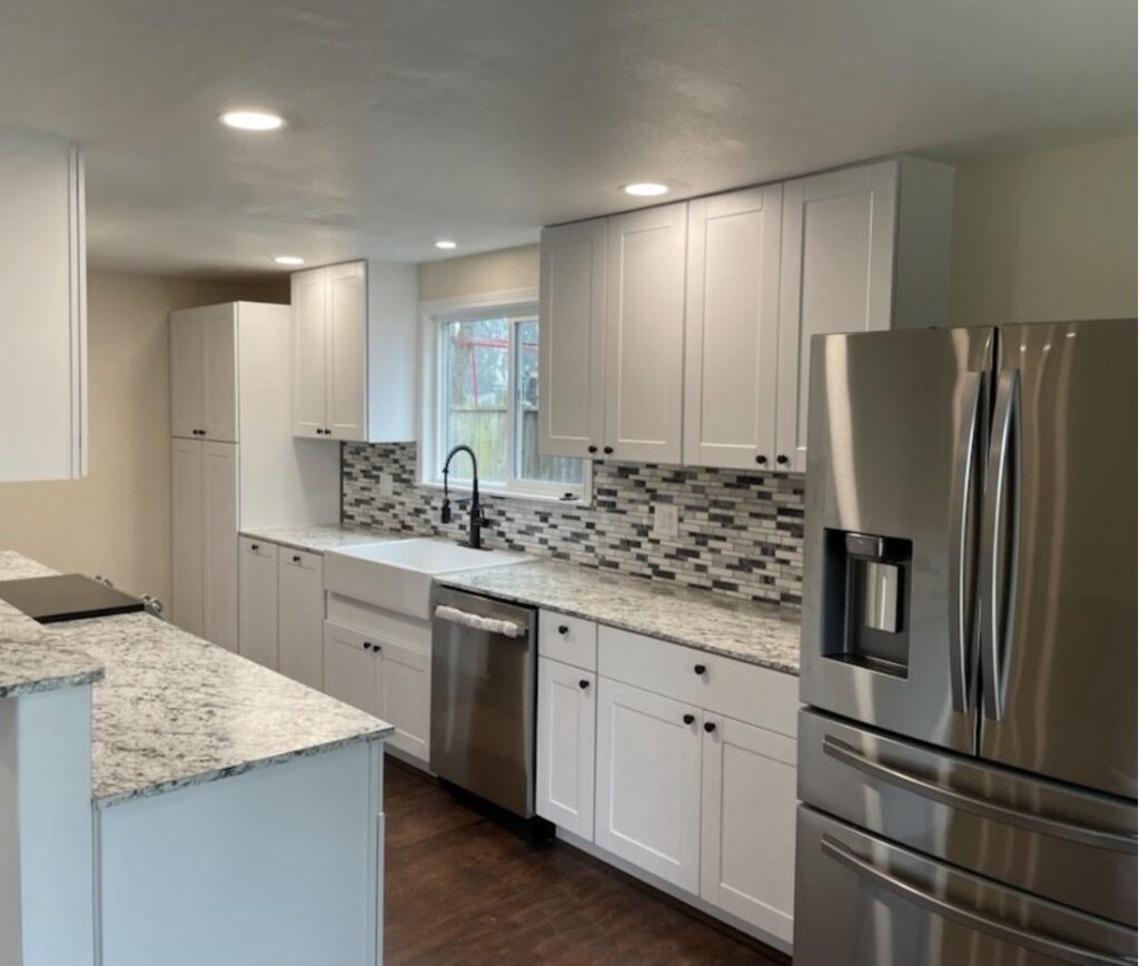 Modern kitchen remodel with new white cabinets, quartz countertops, mosaic tile backsplash, LVP flooring and stainless steel appliances.