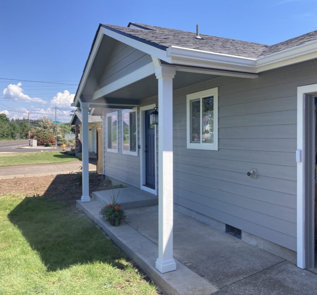 Siding replacement in Pleasant Hill, Oregon featuring new gray exterior siding, white trim, updated windows, and a covered front porch.
