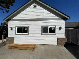 Replacement window installation in Eugene, Oregon with two new horizontal sliding windows, white trim, and finished exterior siding.