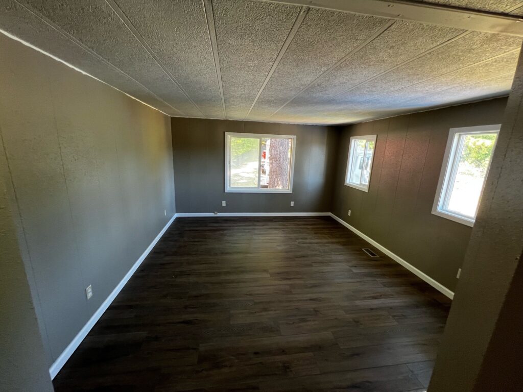 Interior room with replacement windows installed in Eugene, Oregon and finished with white trim, dark flooring, and painted walls.