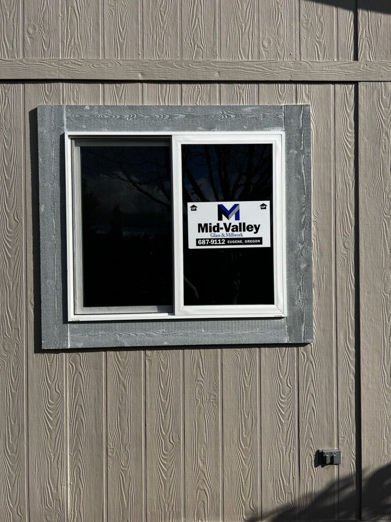 New horizontal sliding window installation in Springfield, Oregon with white frame and exterior trim on vertical siding.