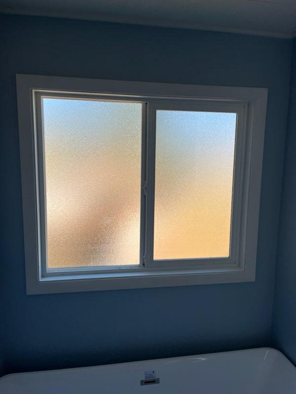 Horizontal sliding replacement window installed in a bathroom in Veneta, Oregon with privacy glass and finished white trim.